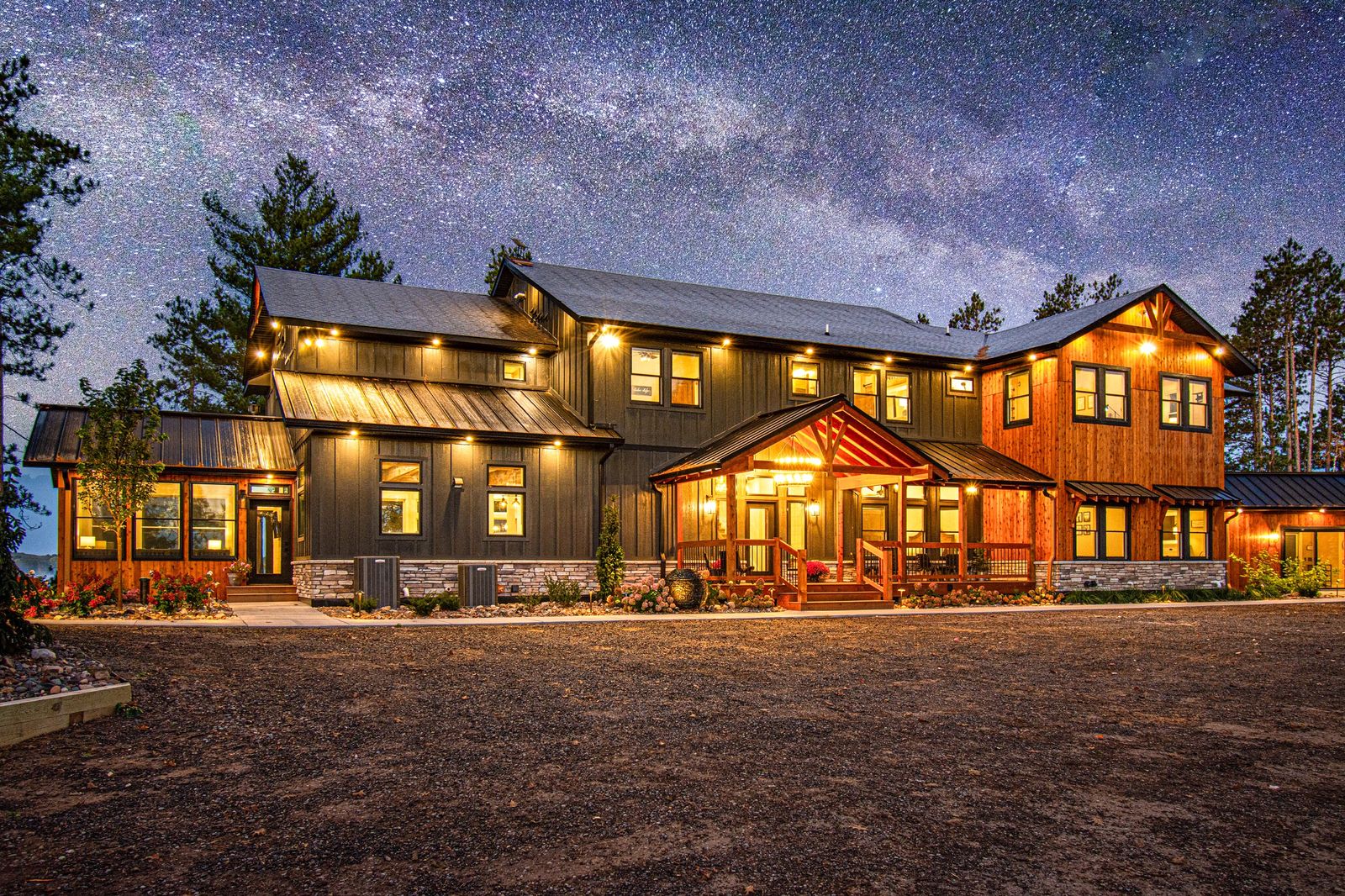 The timber and stone lodge glowing at dusk beneath tall red pines